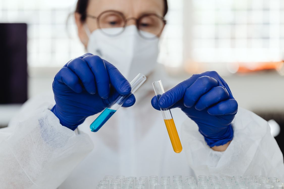 Cientista com máscara de proteção segurando amostras em laboratório