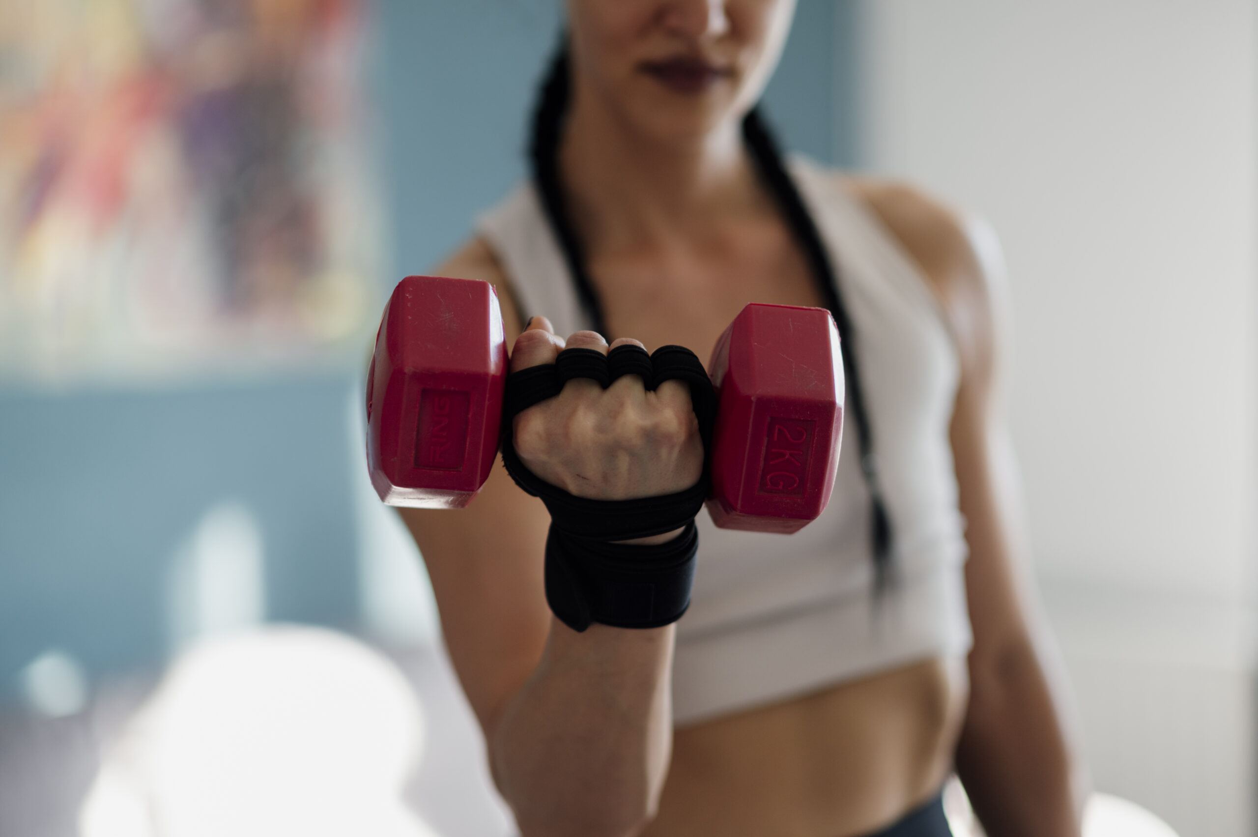 Pessoa treinando com halteres durante exercício em casa